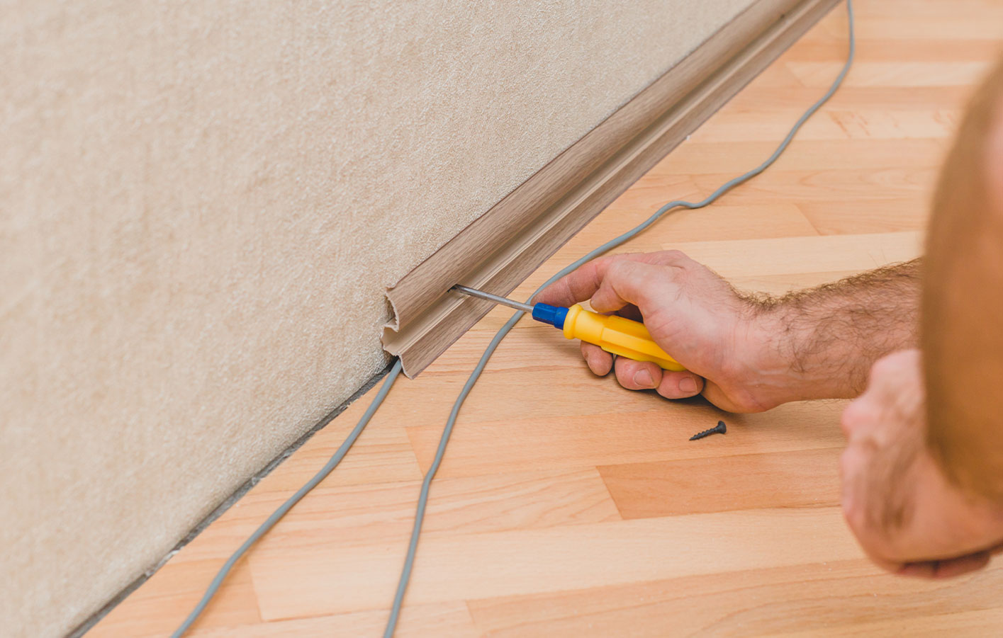 Leisten, Bodenleisten Boden-Zubehör - Boden verlegen und Kabel verstecken Mann versteckt Kabel in Fußleiste - Sockelleiste