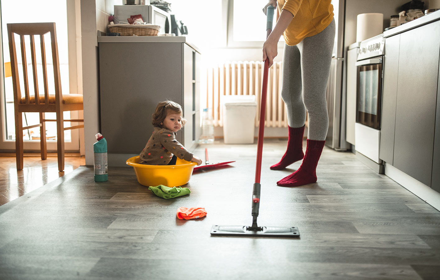 Designvinylboden - umweltbewusst, vielseitig + hygienisch moderne offene Küche - Mutter wischt Bodenbelag - Kind sitzt daneben